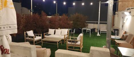 An outdoor seating area with wooden furniture and string lights.