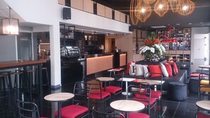 A modern restaurant interior with high tables and chairs, a bar area, and a seating section with red cushions. - Avenue J Hotel Central Market KL (Kuala Lumpur)