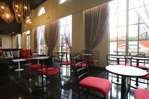 A modern cafe with black and red chairs, white tables, and large windows with curtains. - Avenue J Hotel Central Market KL (Kuala Lumpur)