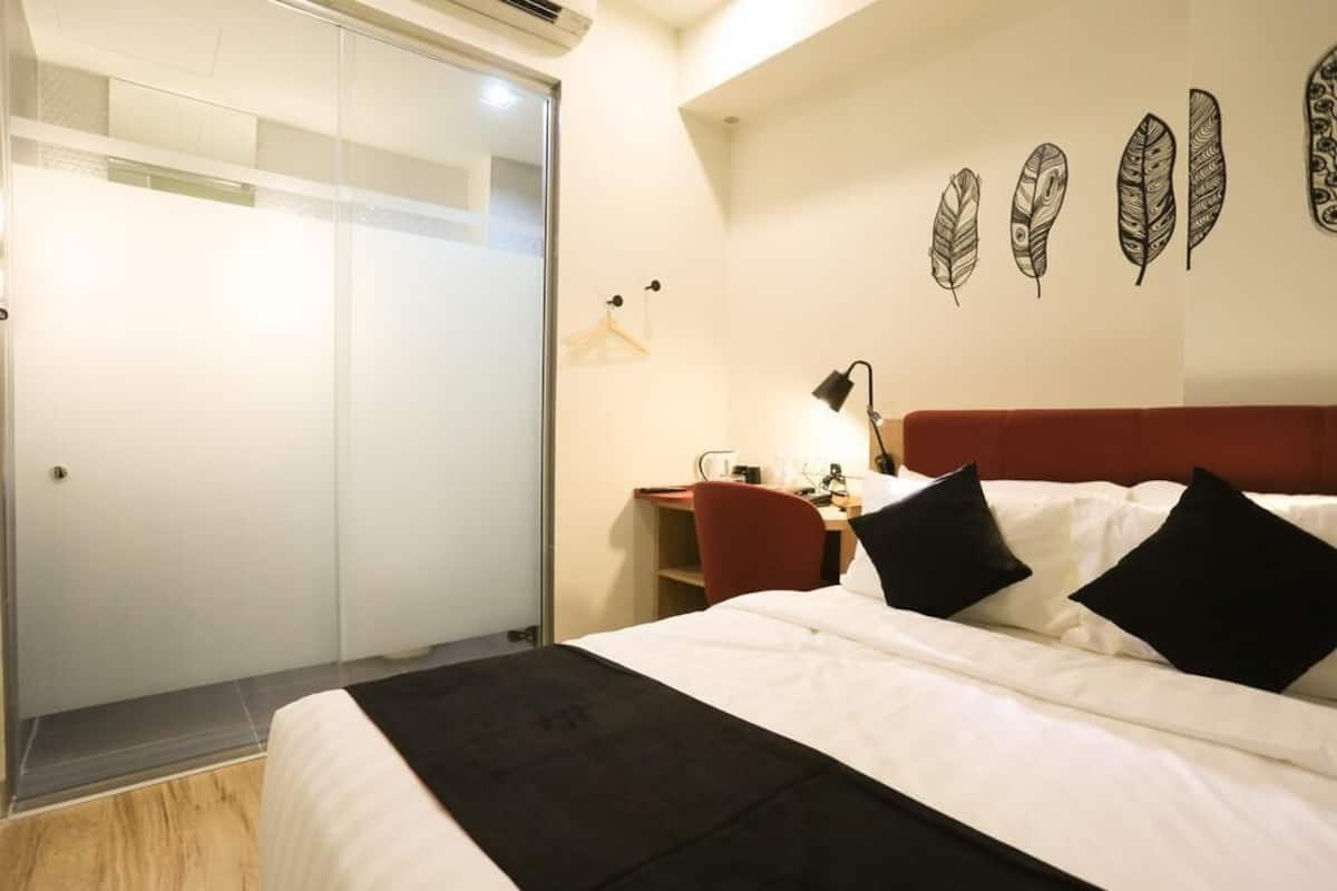 A hotel room with a bed, a desk, a chair, and a wardrobe.
