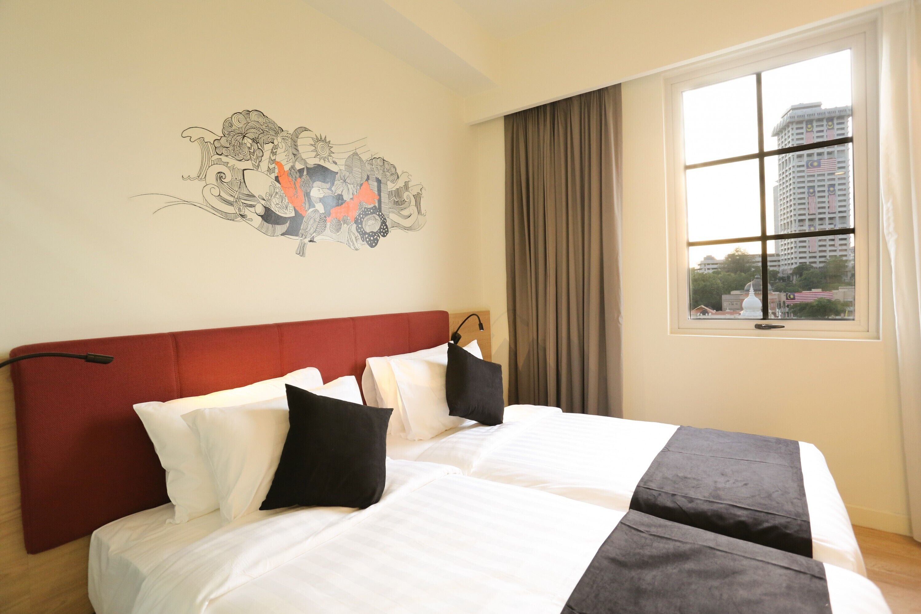 Habitación de hotel con una cama grande, cabecera roja, ventana con cortinas y un mural en la pared.