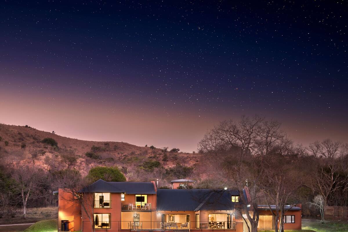 A two-story house with a balcony, a patio, and a view of the night sky.