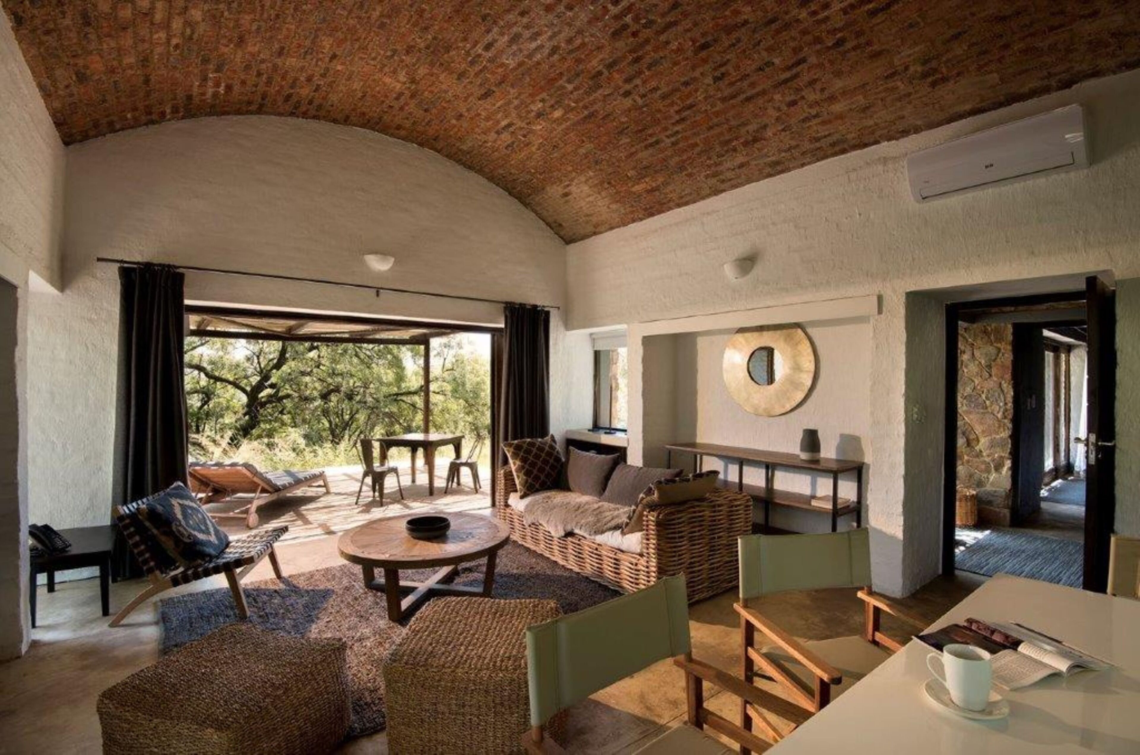 A spacious living area with a high ceiling, wicker furniture, and a large window providing a view of the outdoors.