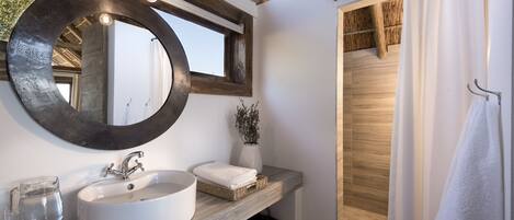 A modern bathroom with a large mirror, white sink, and wooden vanity.