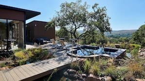 A modern outdoor pool area with a wooden deck, lounge chairs, and a hot tub. - Cradle Boutique Hotel (Muldersdrift)