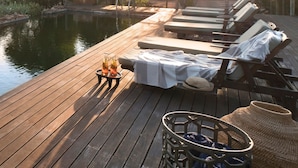 A wooden deck with lounge chairs and a pool, surrounded by trees and a sunset. - Cradle Boutique Hotel (Muldersdrift)