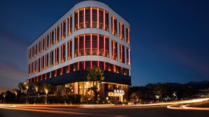 Un hôtel moderne doté d’une façade incurvée, de grandes fenêtres et d’une enseigne lumineuse.