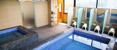 An indoor swimming pool with tiled walls and a separate area for changing.