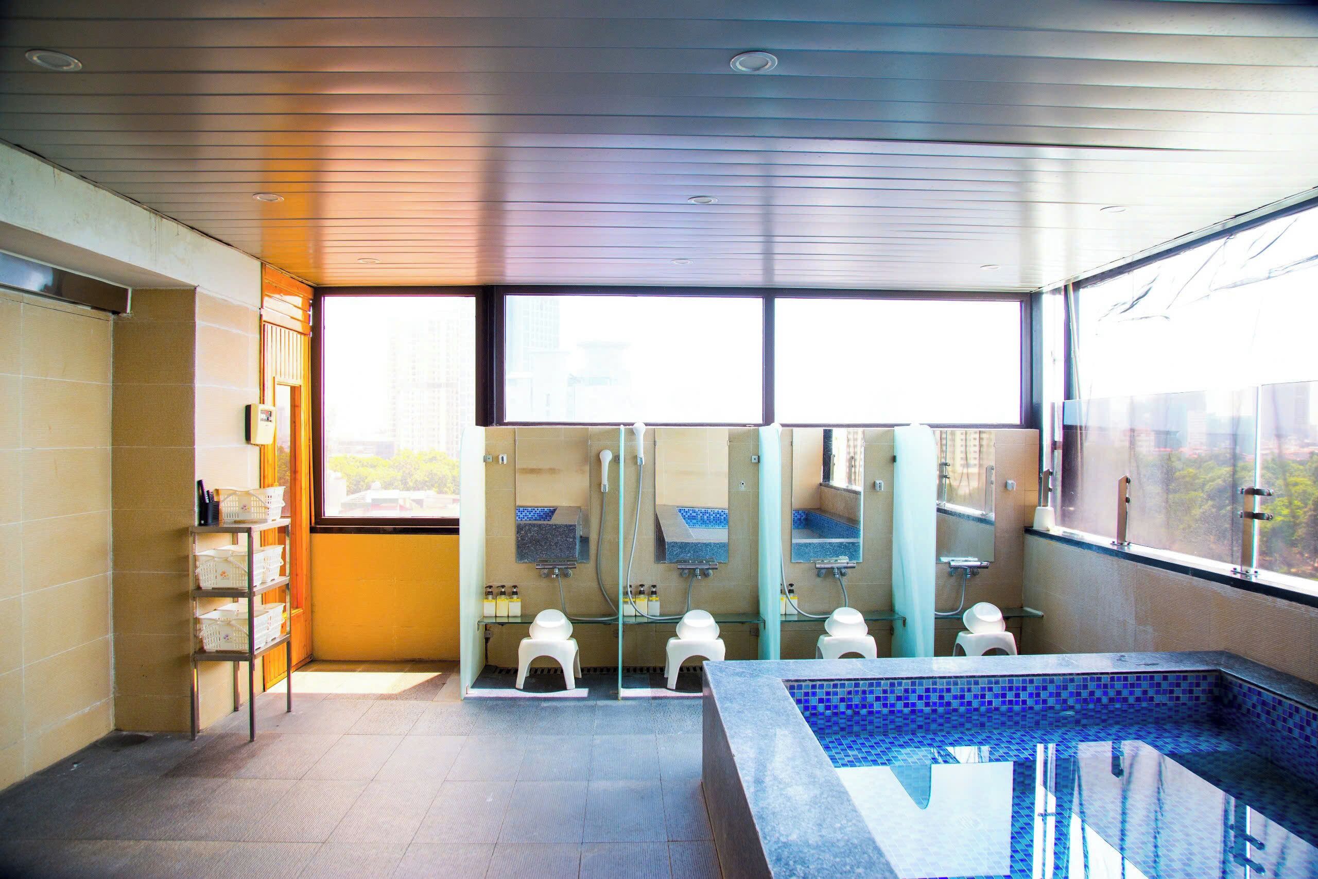A modern bathroom with a large window, a small pool, and a shelf with baskets.