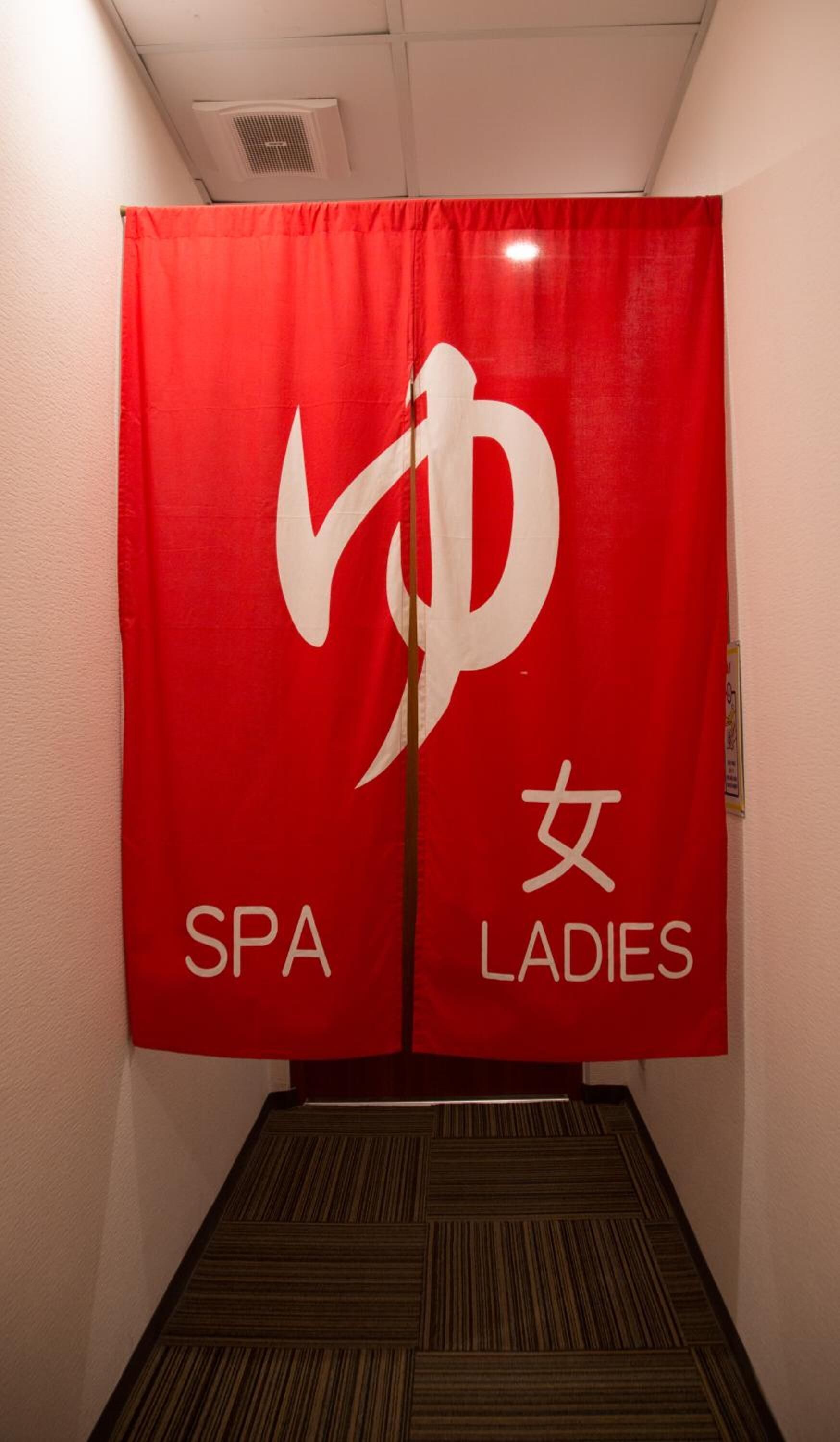 A red banner with the Spa Ladies logo and text in a hallway.