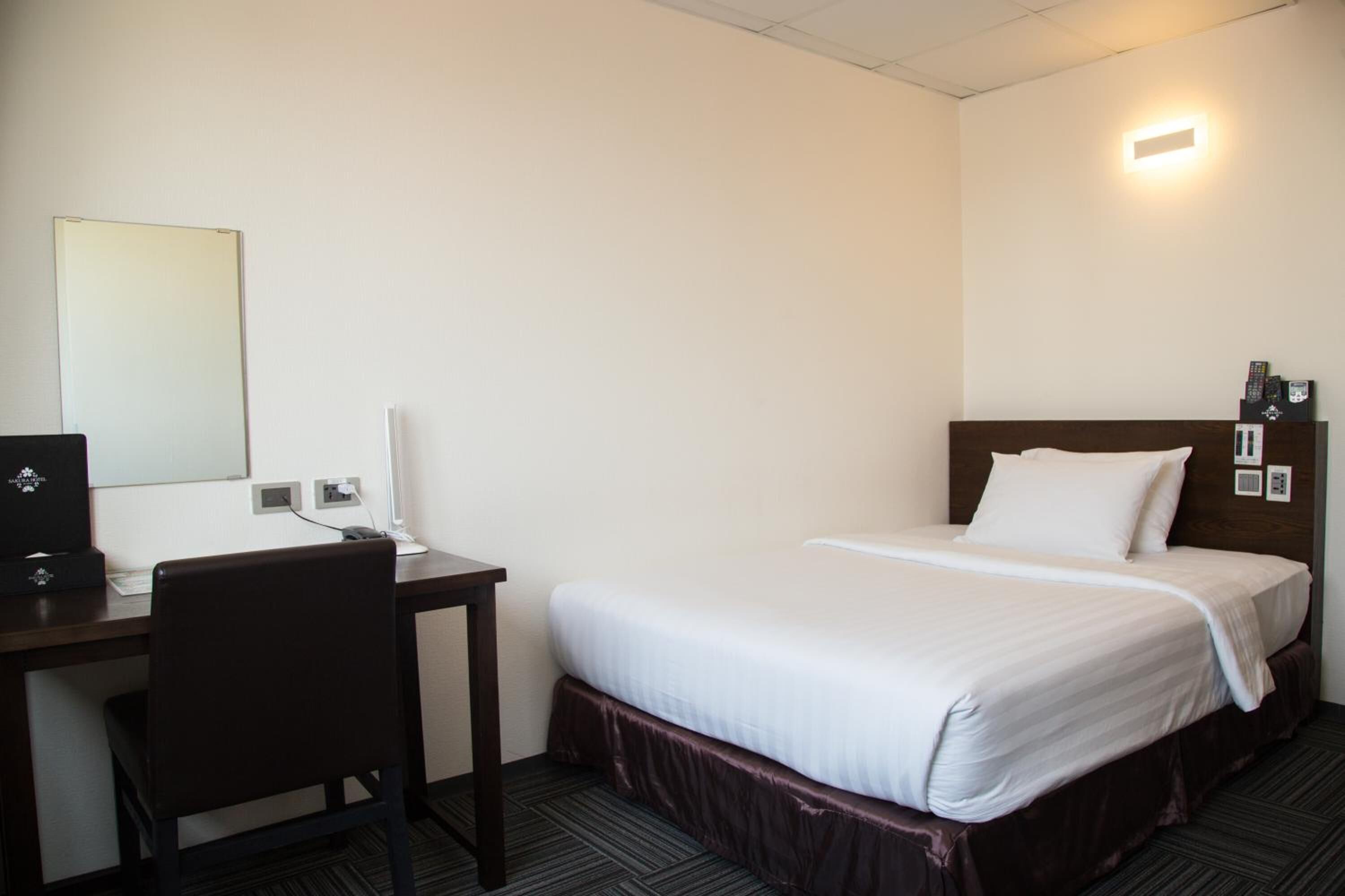 Una habitación de hotel con una cama individual, un escritorio con computadora y una silla.