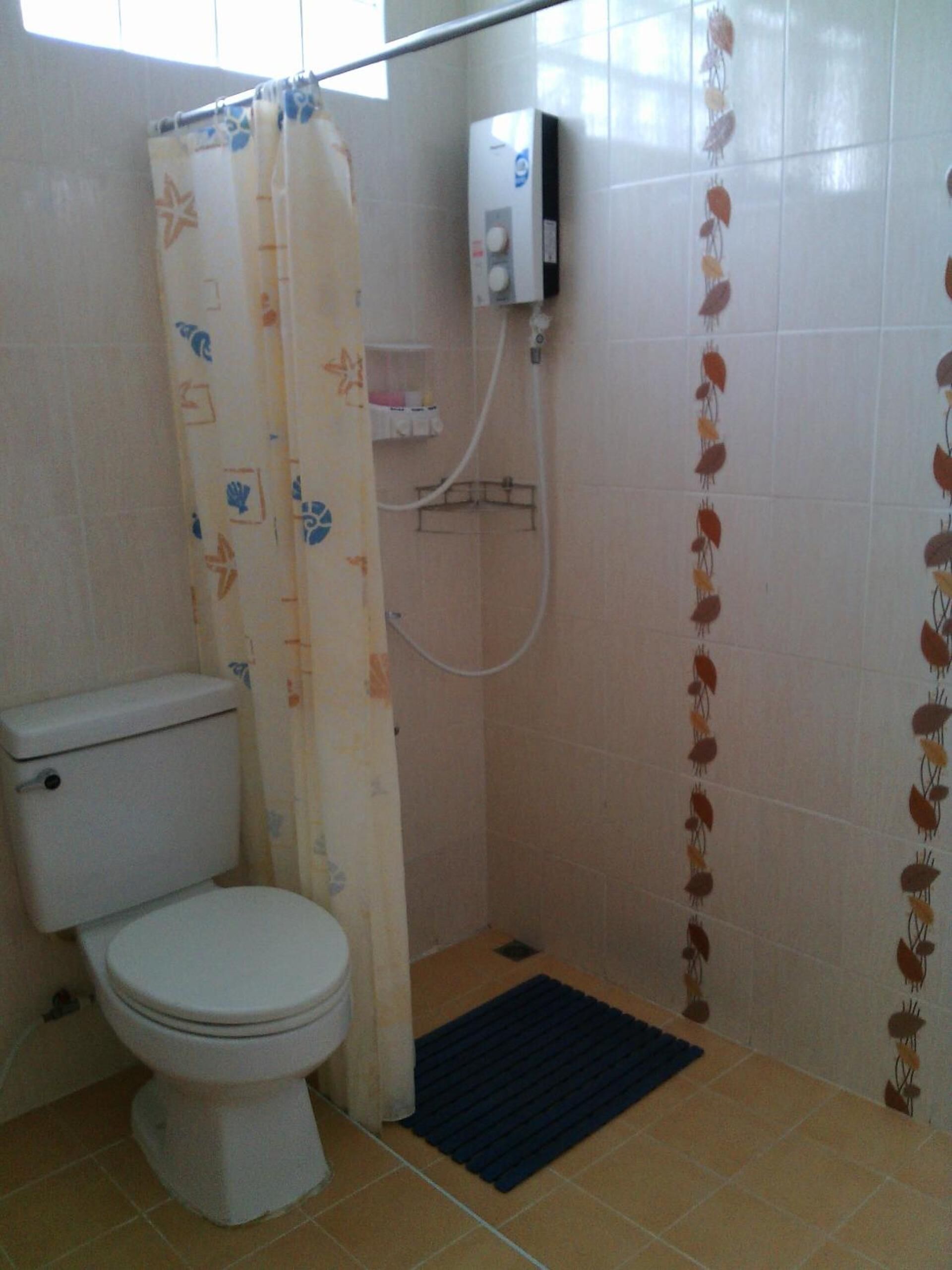 Un baño pequeño con inodoro, ducha y calentador a pared.