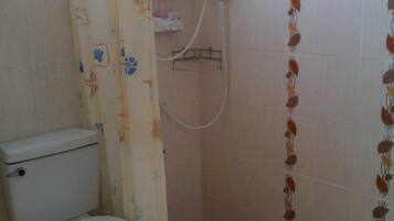 Un baño pequeño con inodoro, ducha y calentador a pared.