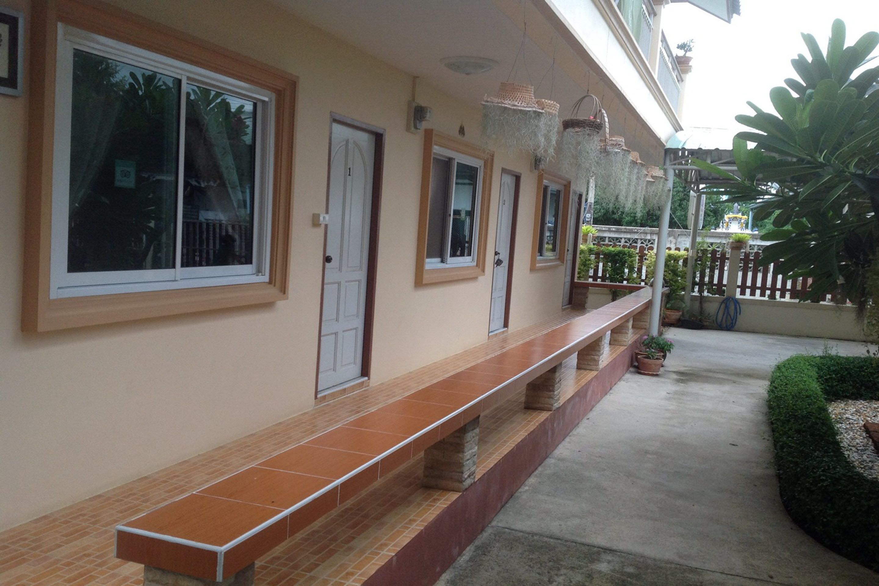 A building with multiple doors and windows, a long bench, and potted plants.
