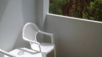 Un pequeño balcón con dos sillas de plástico blanco y una mesa pequeña.