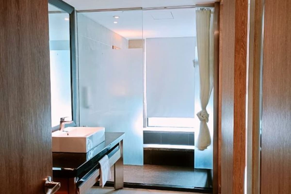 A modern bathroom with a glass shower enclosure, a sink, and a bench.
