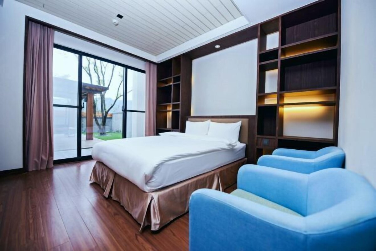 Une chambre d’hôtel moderne dotée d’un grand lit, d’un coin salon et d’étagères intégrées.