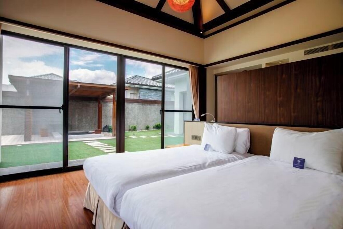 Une chambre d’hôtel avec deux lits, de grandes fenêtres et une vue sur une cour intérieure.