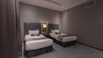 A hotel room with two beds, a nightstand, a lamp, and a mirror.