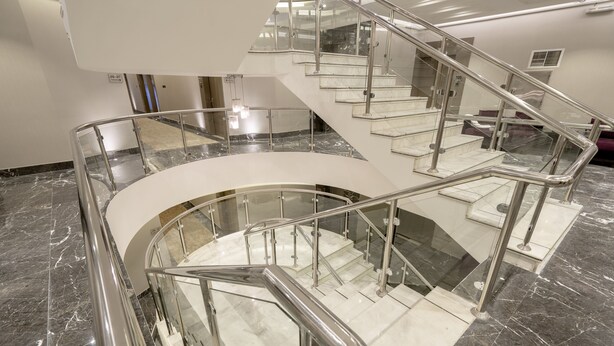 Ein mehrgeschossiges Interieur mit Marmorböden, Glasgeländern und Metallhandläufen.