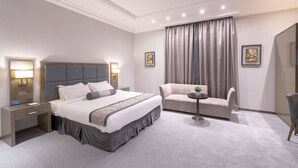 Ein modernes Hotelzimmer mit einem großen Bett, einer Couch, einem kleinen Tisch und einem Kleiderschrank.