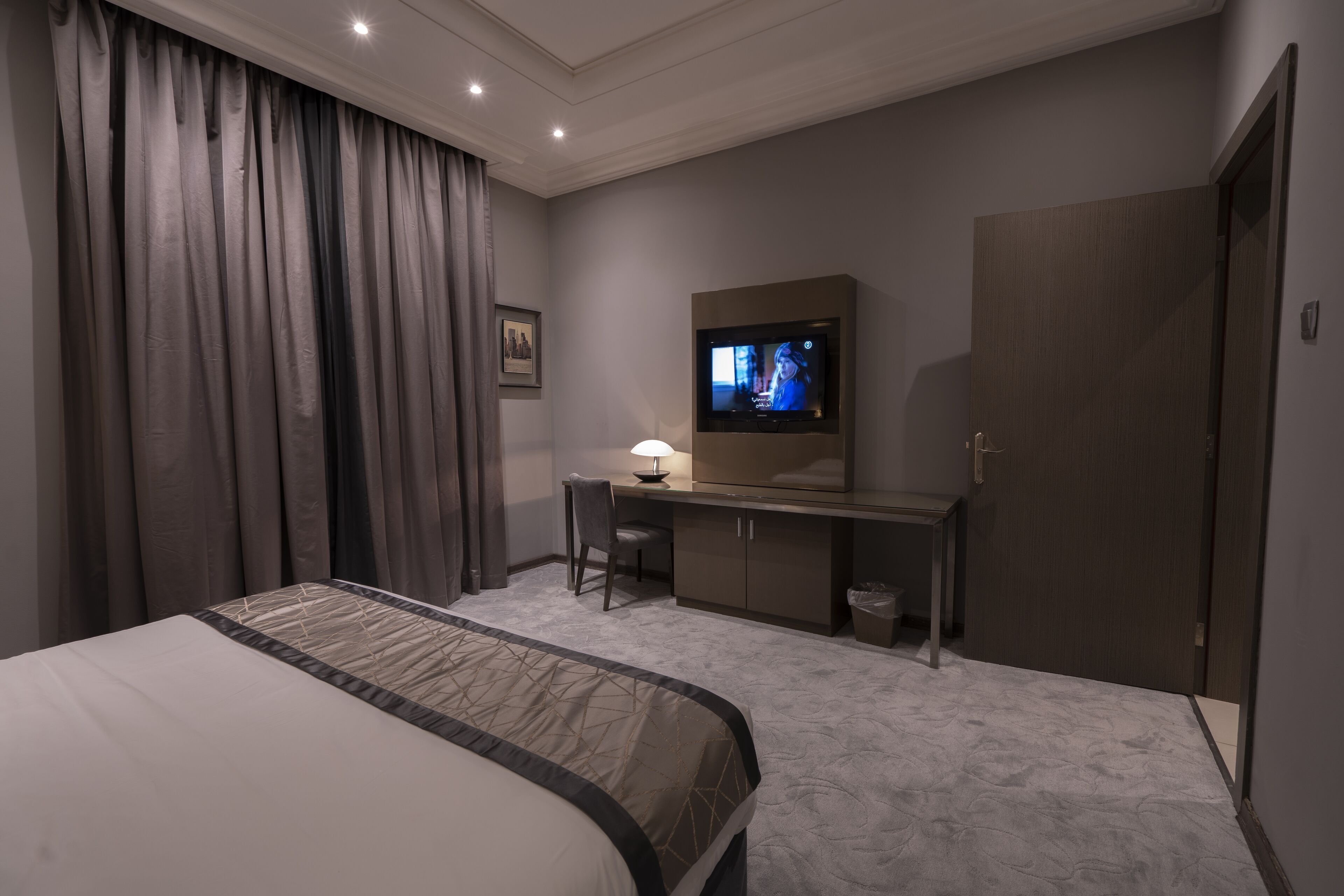 Ein Hotelzimmer mit Bett, Schreibtisch, Fernseher und Kleiderschrank.