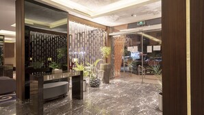 Eine moderne Lobby mit Marmorboden, einer Rezeption und einer Wand mit vertikalen Elementen.