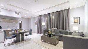 Ein modernes Wohnzimmer mit einem grauen Sofa, einem Couchtisch und einem Essbereich mit Tisch und Stühlen.