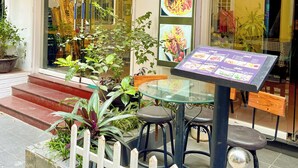 A restaurant named 'Amy Hostel' with a glass entrance, outdoor seating, and a menu board. - Amy Hostel Hue (Hue)