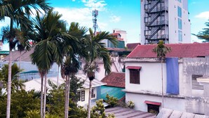 A multi-story building with a red-tiled roof, surrounded by palm trees and other greenery. - Amy Hostel Hue (Hue)