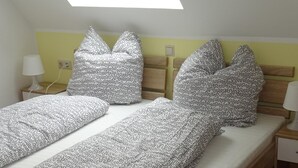 A bedroom with two beds, each with patterned bedding and a wooden headboard. - Hotel Einstein (Bad Krozingen)