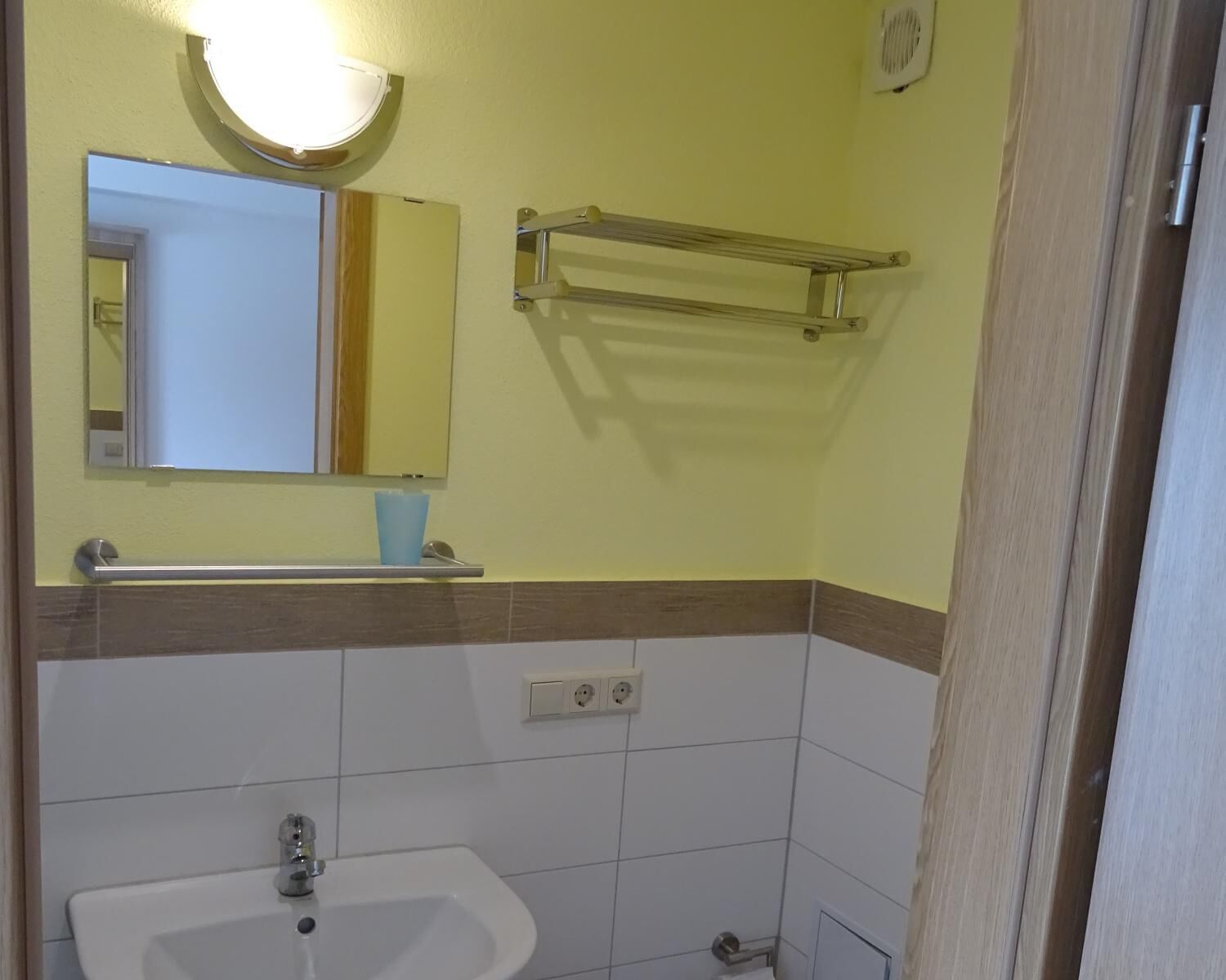 Ein Badezimmer mit Waschbecken, Spiegel, Handtuchhalter und einer Lampe.
