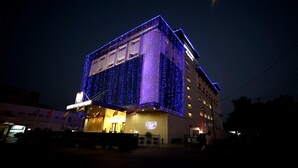 A hotel with a modern design, featuring a prominent entrance and a large illuminated logo on the facade. - Goutham Grand Hotel (Tenali)