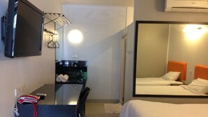 A hotel room with a bed, a desk with a chair, a TV mounted on the wall, and a large mirror. - Natpob Sleep Station Motel (Chiang Rai)