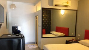 A hotel room with a bed, a desk, a mirror, and an air conditioning unit. - Natpob Sleep Station Motel (Chiang Rai)