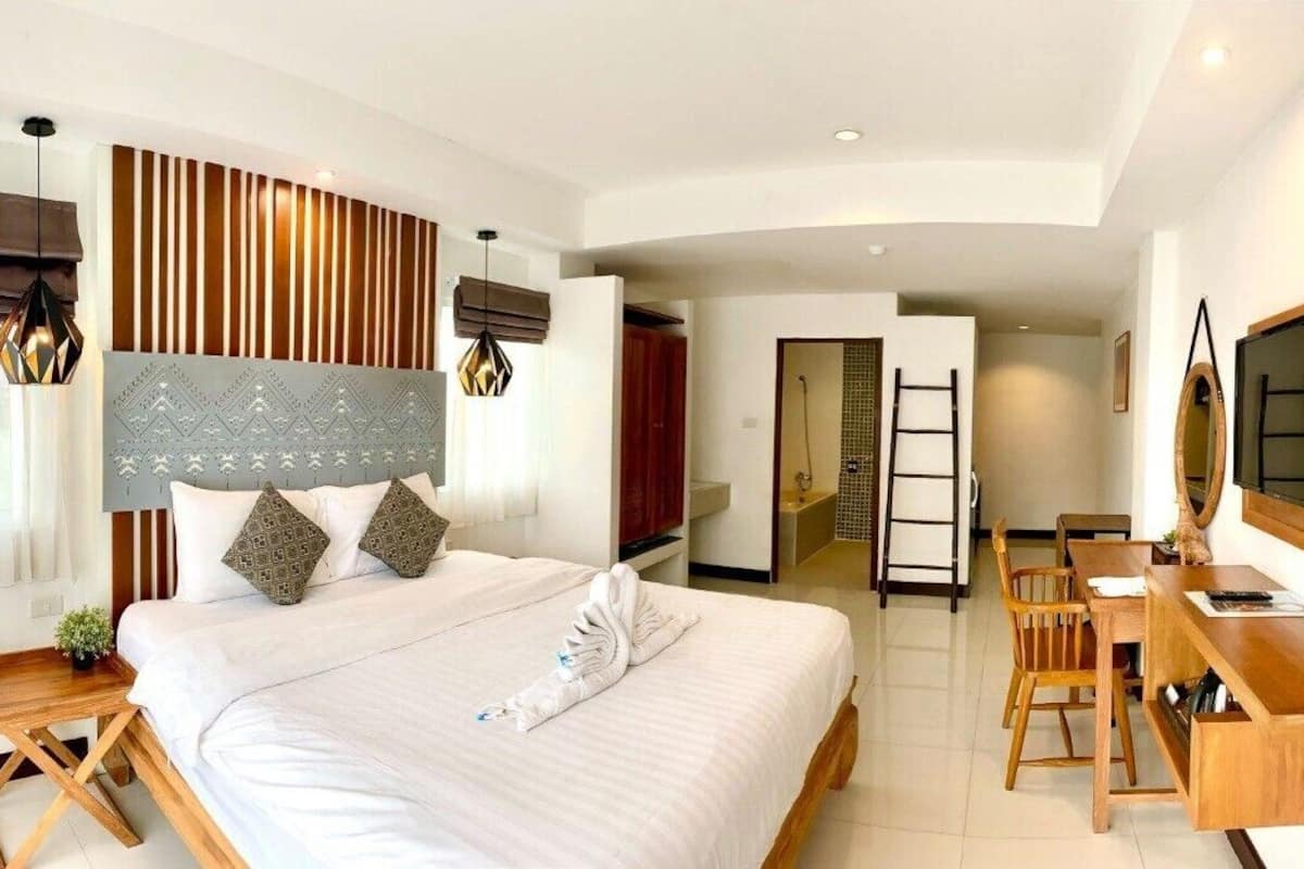 Una habitación de hotel moderna con una cama grande, un escritorio, un televisor y un espejo.