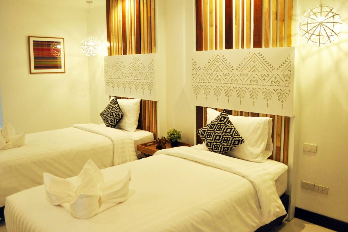 Habitación de hotel con dos camas, cabeceros de madera y un panel decorativo en la pared.