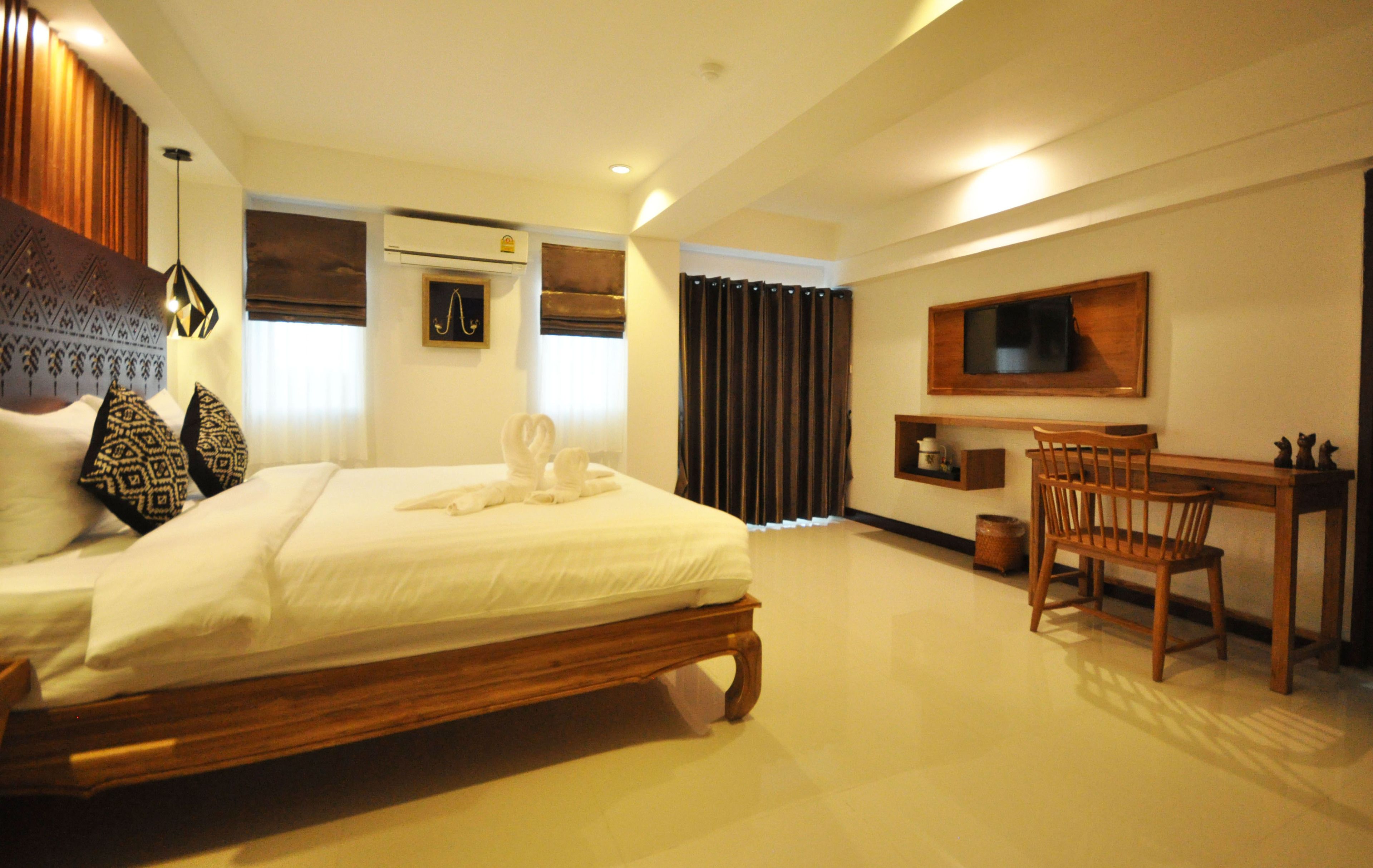 A hotel room with a bed, a desk, a chair, a television, and a window with curtains.