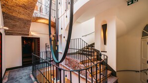Un interior moderno con una escalera espiral, una pared de ladrillo y un piso con estampado.