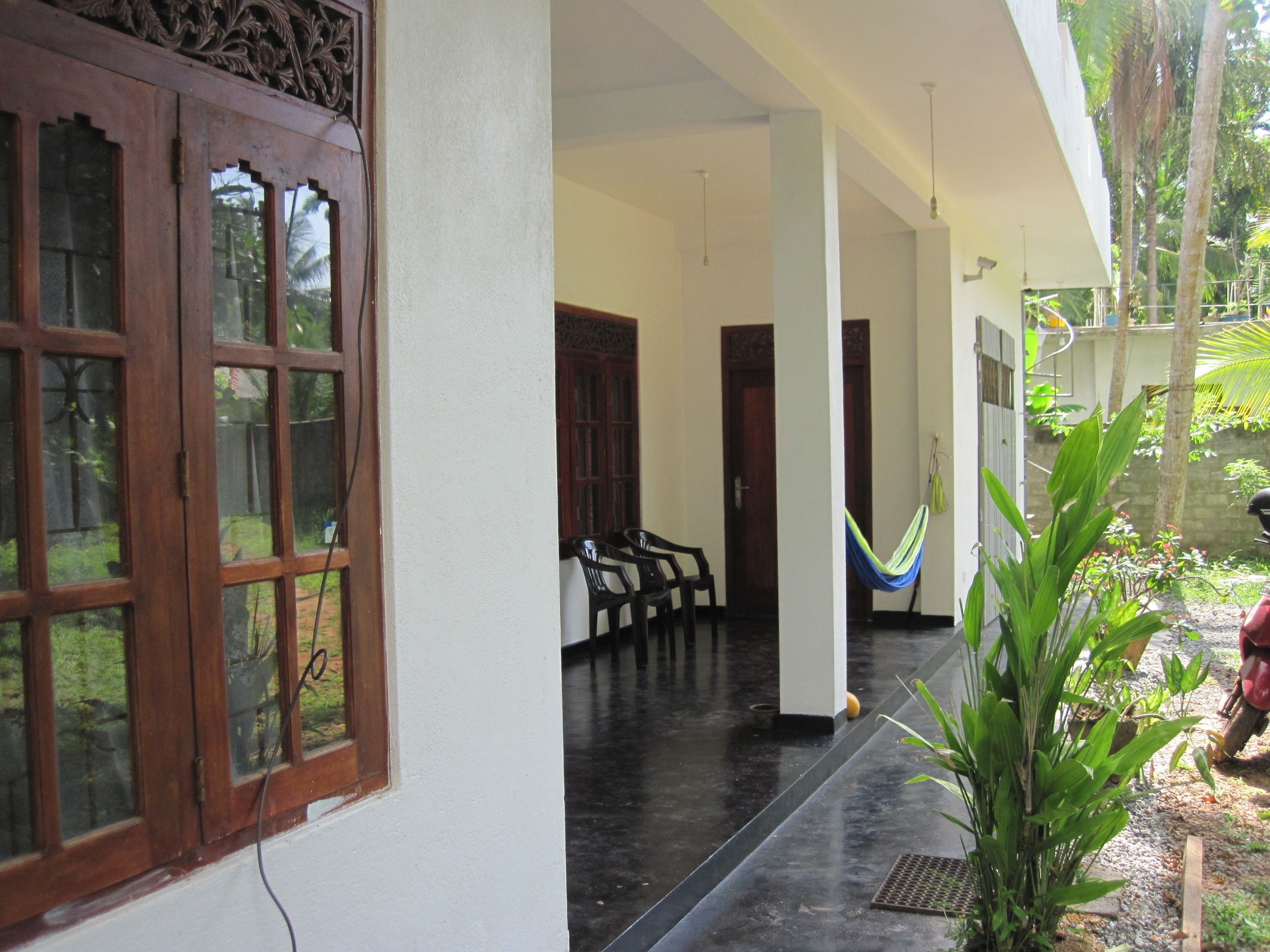A covered outdoor area with a black floor, wooden doors, and a hammock.