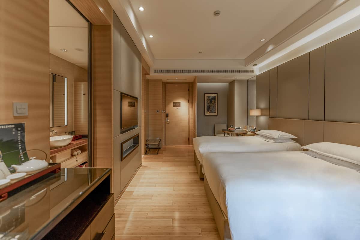 Hotelkamer met een groot bed, een televisie, een nachtkastje en een badkamer met wastafel en spiegel.