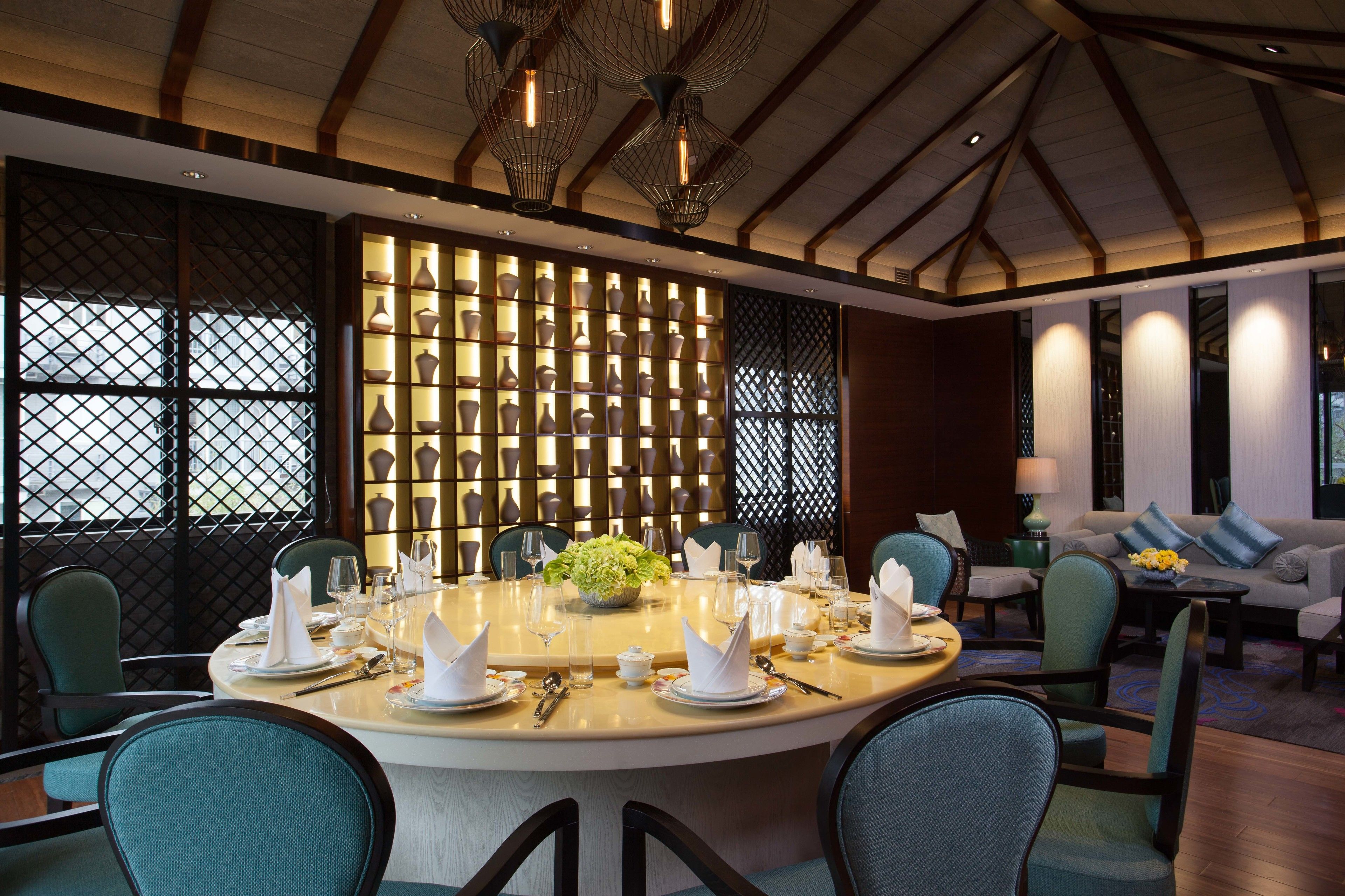 A modern dining area with a round table set for a meal, surrounded by chairs.