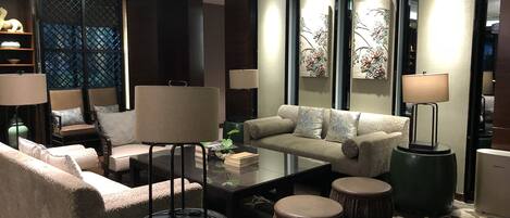 Una sala de estar moderna con un sofá, sillones, una mesa de centro y dos mesitas de noche con lámparas.