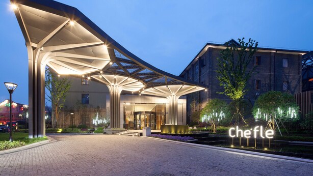 Ein moderner Hotelzugang mit einem überdachten Gang, einer gut beleuchteten Lobby und einem Schild mit der Aufschrift "Chefle".