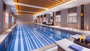 Ein moderner, innenliegender Schwimmbereich mit langem, schmalem Design, Liegebereichen und stimmungsvoller Beleuchtung.