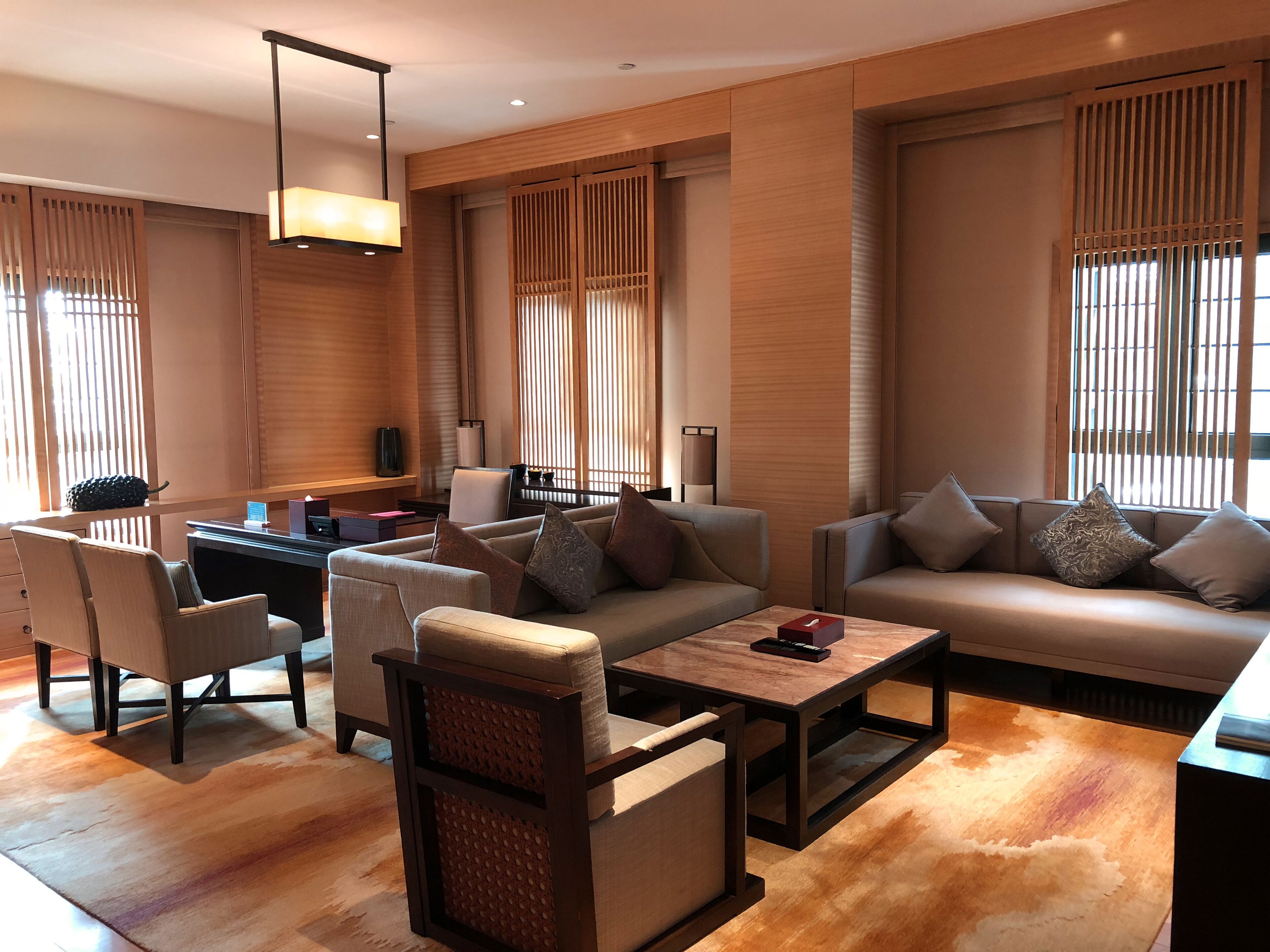 A modern living room with a sofa set, a coffee table, and a side table. There is a lamp, a chair, and a small table with a vase.
