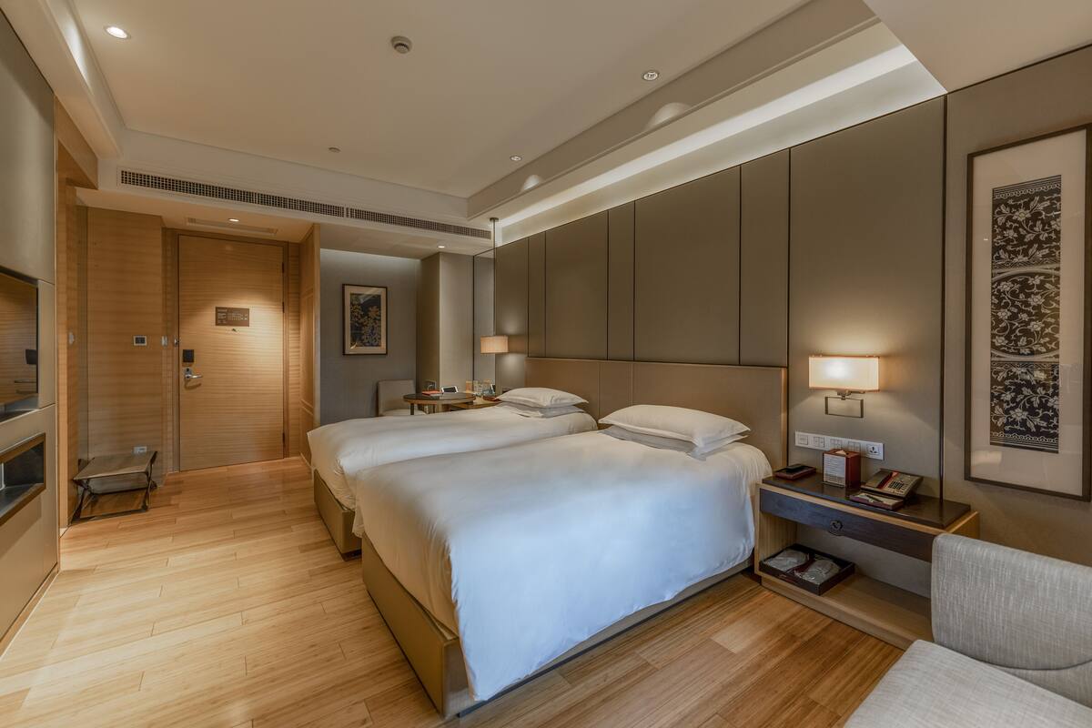 Een hotelkamer met een groot bed, nachtkastjes, een bureau en een stoel.