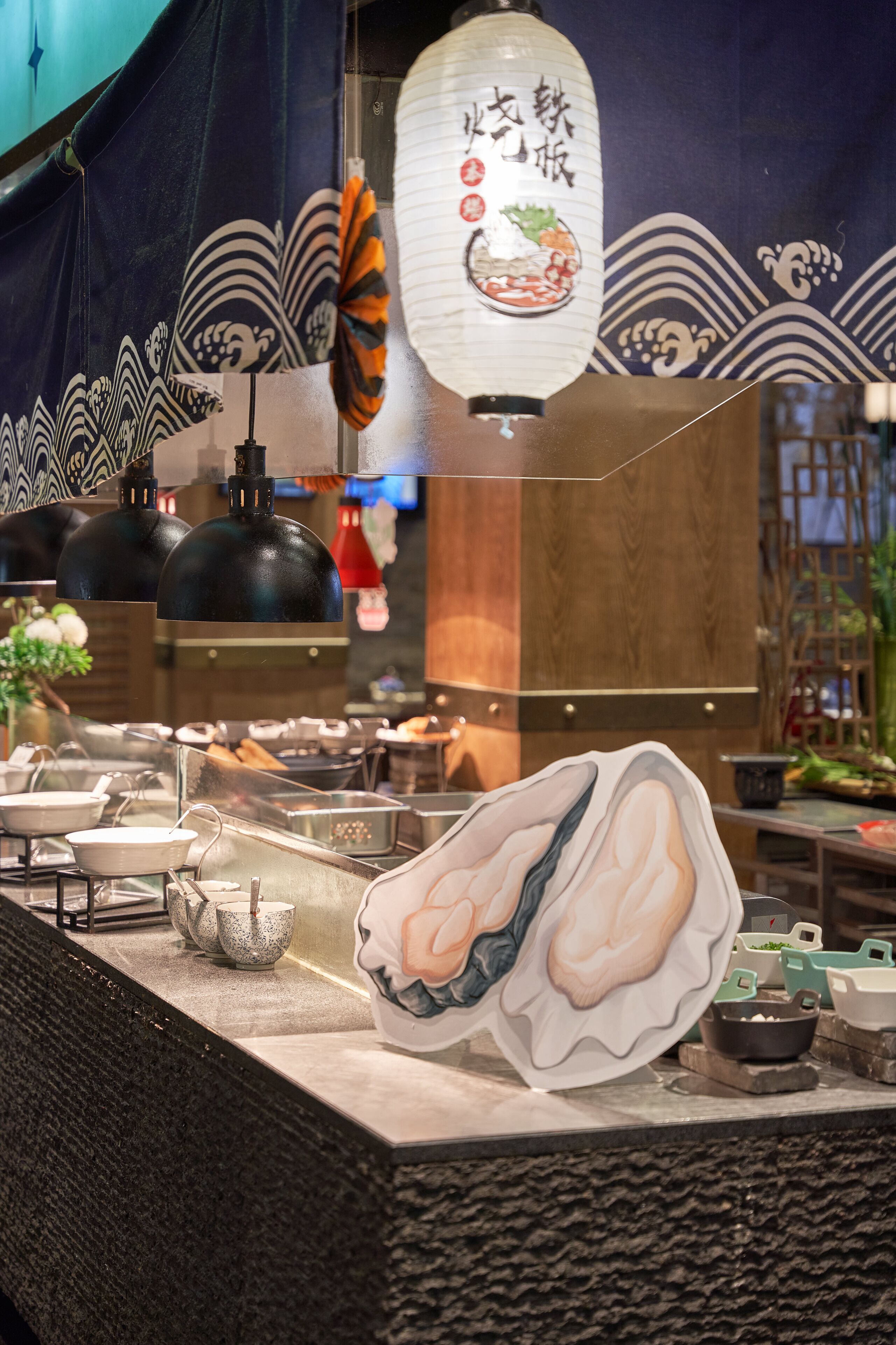 Een restaurant interieur met een sushi presentatie, zwarte hanglampen en een traditionele Japanse lantaarn.