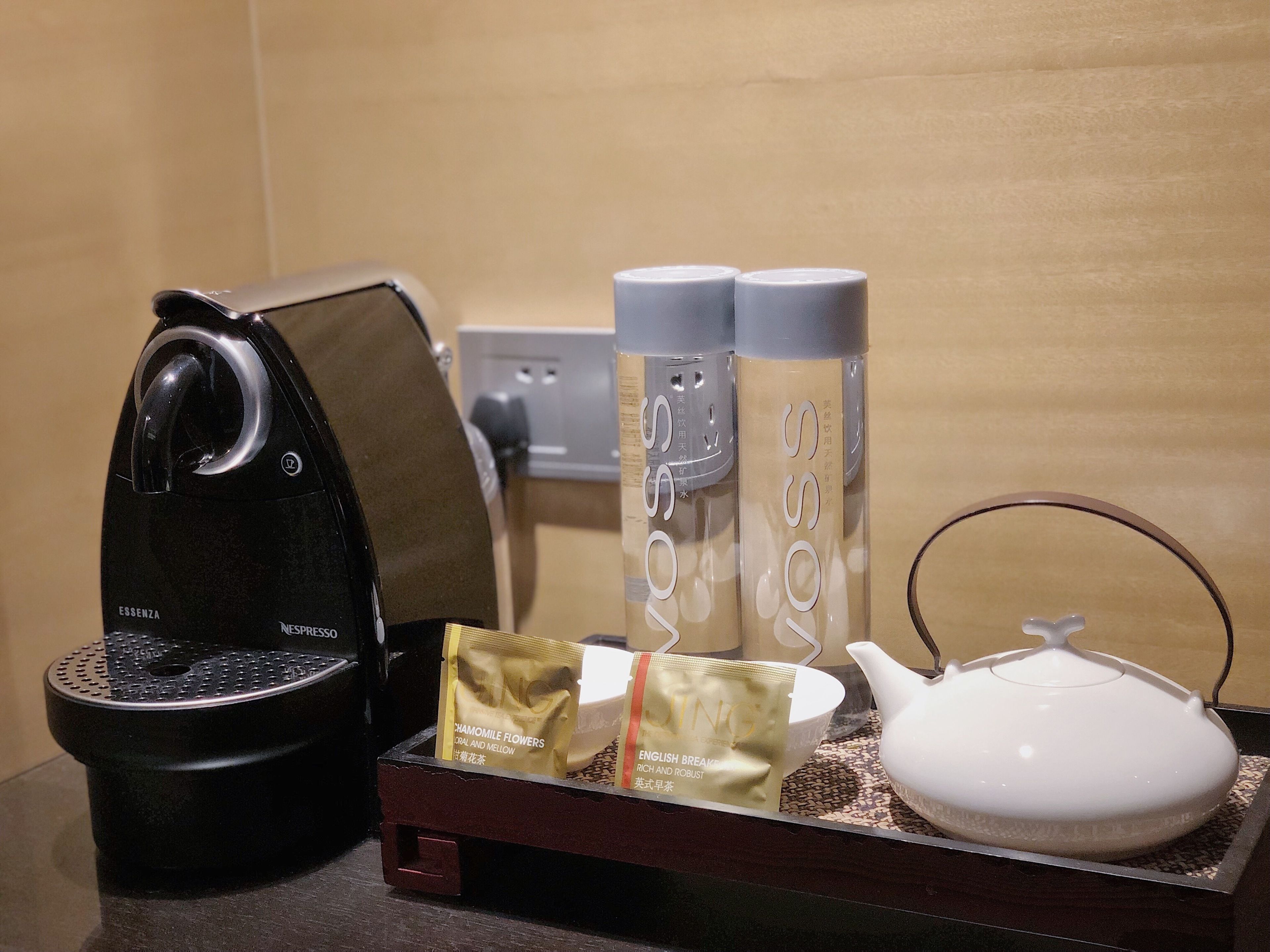 A coffee maker, two bottles of water, a teapot, and a tray with tea bags.