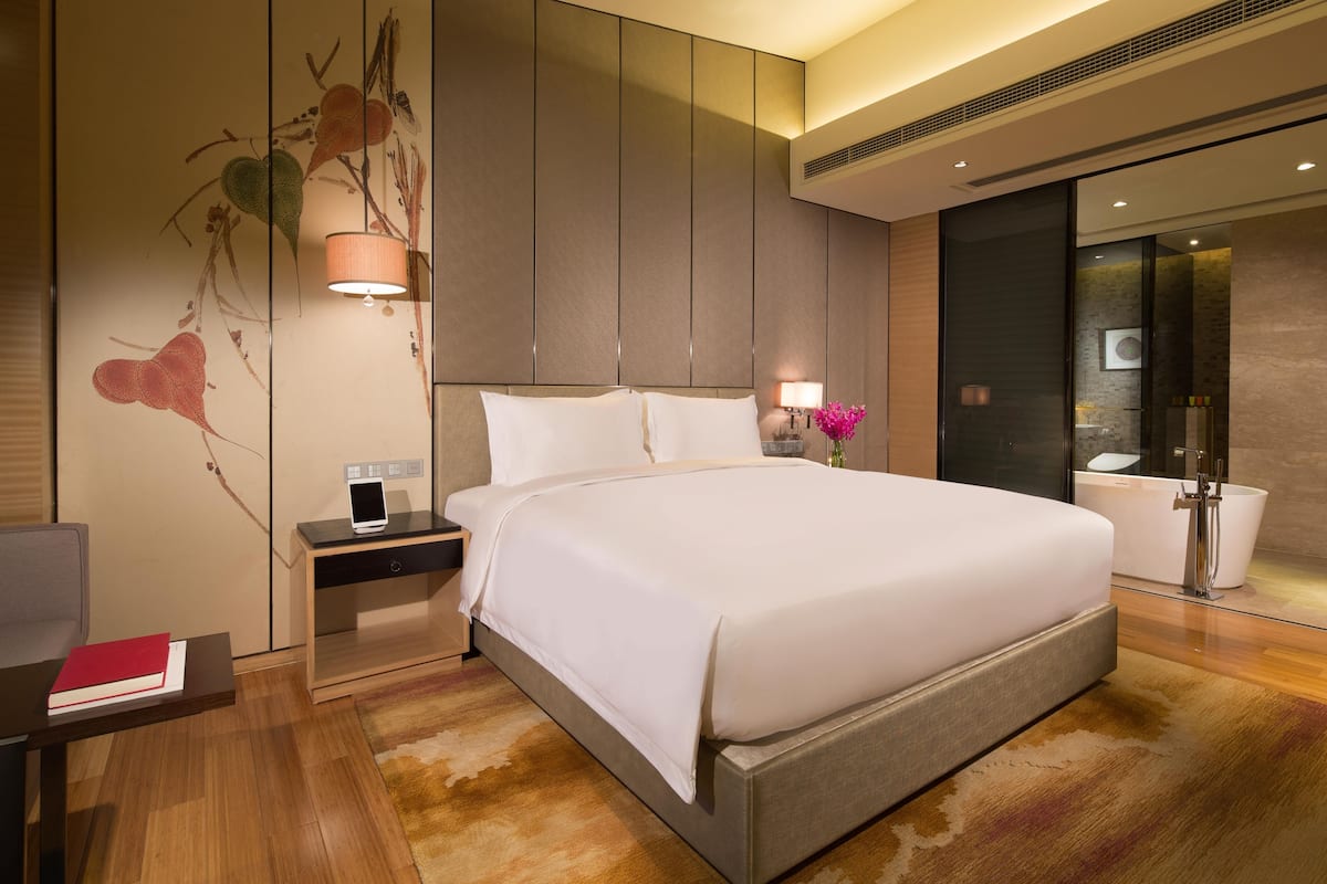 Een moderne hotelkamer met een groot bed, nachtkastjes, een bureau en een badkamer met een bad.